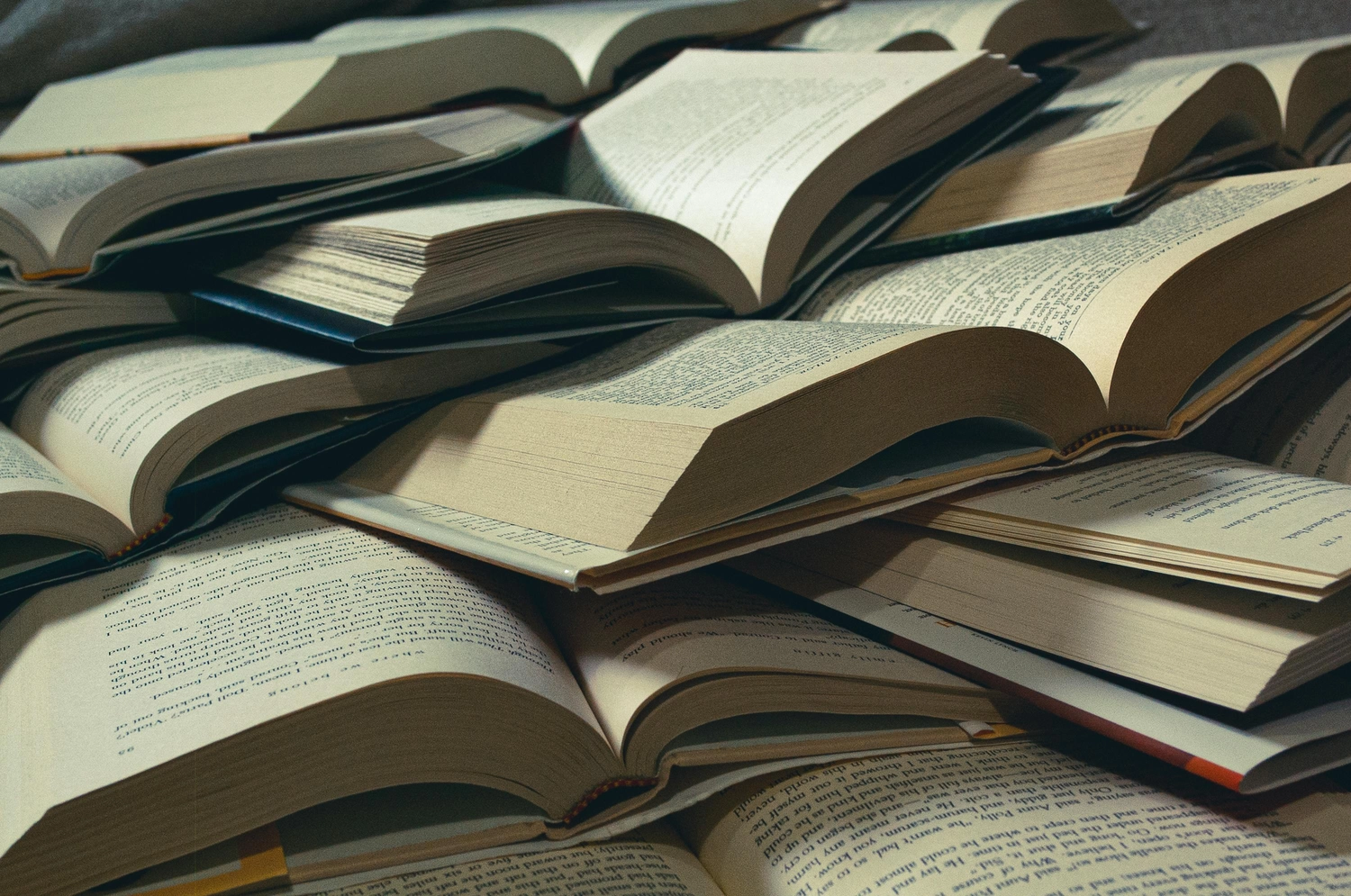 Prof. Dr. Marcus Mittenzwei - Hochschullehrer - Ein großer Stapel offener Hardcover-Bücher, die wahllos übereinandergestapelt sind und deren beschriebene Seiten sichtbar sind.